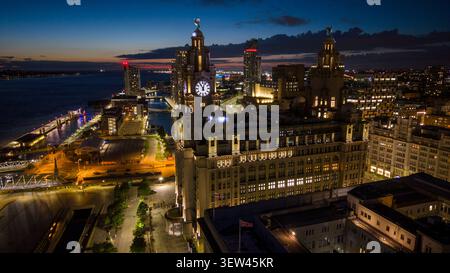Eine Drohnenaufnahme der Hafenpromenade von Liverpool bei Nacht, mit dem Liver Building Stockfoto