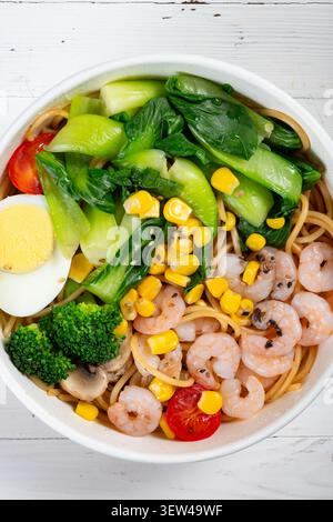 Blick von oben leichte, frittierte Pasta mit hohem Fasergehalt aus Olivenöl, garniert mit frischen grünen Garnelen, Bok Choy, Brokkoli, Mais, Kirschtomaten, ein hart gekochtes Ei, an Stockfoto