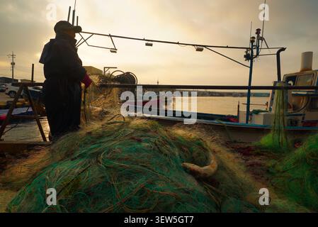 Eine südkoreanische Fischerin, die morgens nach einer Nacht des Fischens ihren Hol einzieht Stockfoto