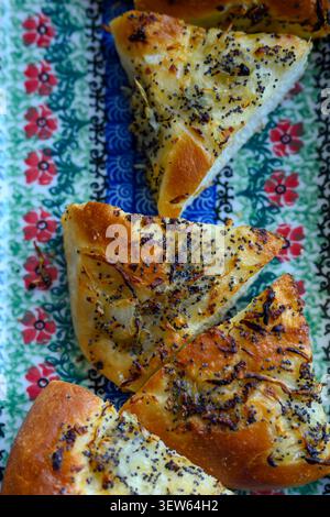 Traditionelles polnisches Cebularz, ein herzhaftes Gebäck aus Zwiebeln und Mohn, serviert auf einer schönen floralen Keramikplatte von Bolslawiec Stockfoto