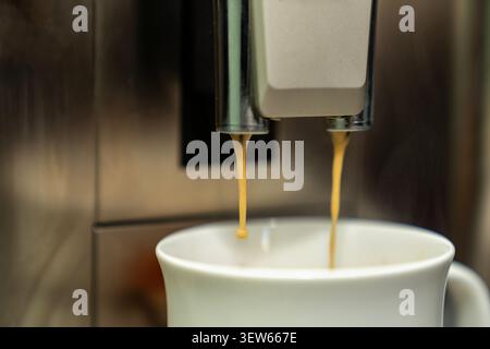 Frisch gebrühter Kaffee in einer Tasse aus der Espressomaschine. Heißes Morgengetränk mit cremigem Schaum. Barista-Stil-Getränk zu Hause oder im Café. Stockfoto