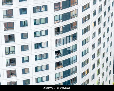 Blick aus der Nähe auf die geschwungene weiße Fassade eines modernen Wohnhauses im Stadtzentrum von Leeds mit Fensterreihen, Balkonen und Konsolen Stockfoto