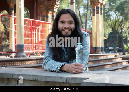 Mann mit Wasserflasche lächelt neben einem maurischen Kiosk Stockfoto