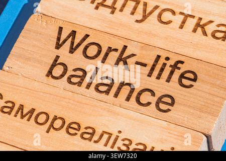 Nahaufnahme der hellen Holzoberfläche mit eingraviertem Text, mit Work-Life-Balance-Konzept in englischer und kyrillischer Schrift, die rustikales Natu hervorhebt Stockfoto