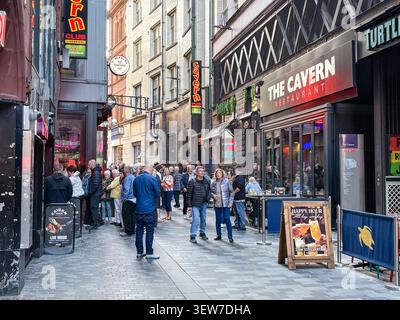 Touristen spazieren entlang der historischen Mathew Street im Stadtzentrum von Liverpool, mit dem berühmten Cavern Club und urbanen Unterhaltungsmöglichkeiten. Stockfoto