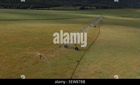 Aus der Vogelperspektive eines Bewässerungssystems, das ein riesiges landwirtschaftliches Feld in der portugiesischen Landschaft mit sanften Hügeln und grünen Weiden bewässert Stockfoto