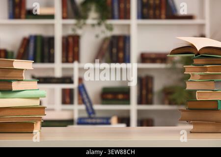 Stapel Bücher auf einem Tisch vor einem Bücherregal Stockfoto