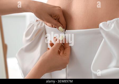 Nahaufnahme des Reißverschlusses der Frau auf weißem Kleidrücken Stockfoto