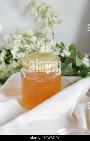 Ein Glas Honig mit Blumen aus Akazien auf dem Tisch, Nahaufnahme Stockfoto