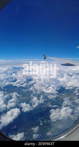 Ansicht aus dem Flugzeugfenster mit Flügeln über Wolken Stockfoto
