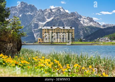 Historisches Luxushotel am Ufer des Misurina-Sees mit majestätischen felsigen Berggipfeln unter sonnigem Himmel, malerischer Alpenreise und Urlaubsziel Stockfoto