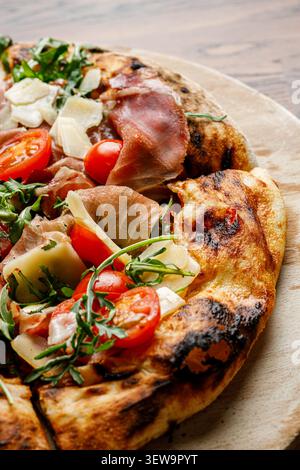 Pizza mit Schinken, Tomaten und Rucola isoliert. Stockfoto