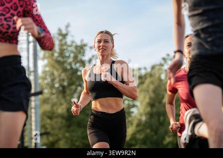 Sportliche Frau, die mit einer Gruppe draußen läuft Stockfoto