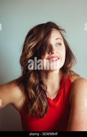 Glückliche junge Frau mit windgeblasenen Haaren, die lächelnd sind Stockfoto