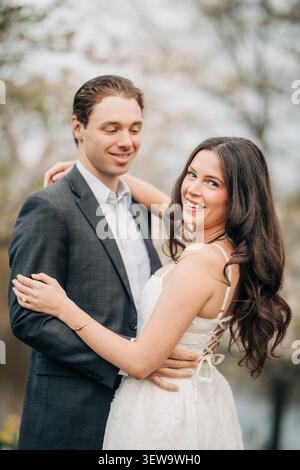Glückliche Frau in weißem Kleid, umarmt vom Mann Stockfoto