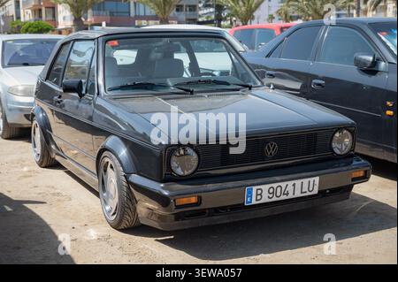 Vorderansicht eines modifizierten schwarzen Volkswagen Golf Mk1 1974-Cabriolets, das auf einem Schottergrundstück geparkt ist, mit abgesenkter Standfläche und kundenspezifischer Leichtmetallfelge Stockfoto