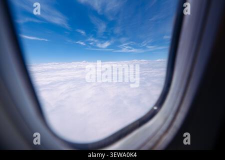 Aus der Vogelperspektive auf Wolkenlandschaft und weit entfernte Berggipfel aus Passagierflugzeugen Stockfoto