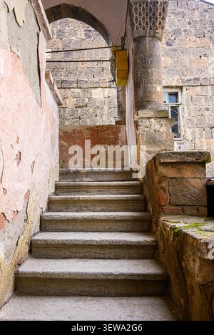 Eine Steintreppe führt durch einen alten Bogengang hinauf. Die Wände zeigen Anzeichen von Witterung und Alter Stockfoto