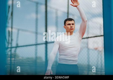 Männlicher Athlet auf einem Basketballfeld im Freien, der während des Sporttrainings die Hand hebt Stockfoto