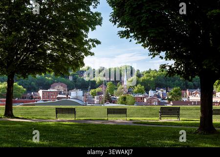 Gerahmter Blick auf die historische Innenstadt von Galena, Illinois, zwischen alten Schatten Bäume im Grant Park, mit drei Parkbänken mit Blick auf die Stadtlandschaft Stockfoto