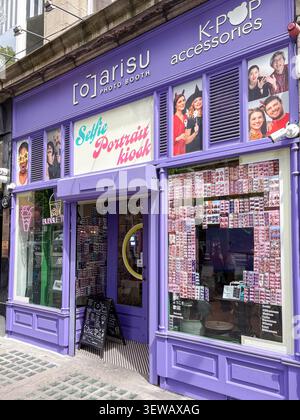 Außenansicht der Arisu K-POP Fotokabine und Zubehörladen. Dublin, Irland. Lila Ladenfront mit Selfie-Porträtschildern und Glasfenstern. Stockfoto