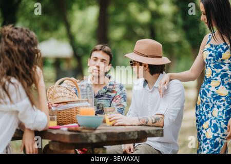 Freunde genießen ein entspanntes Sommer-Picknick in einem grünen Park mit Getränken und Snacks Stockfoto