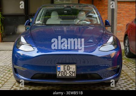 24. Juni 2026, Tiflis, Georgien Ein blaues Tesla Model Y mit georgischen Kennzeichen, von vorne fotografiert. Das Fahrzeug ist wahrscheinlich das Long Range D Stockfoto