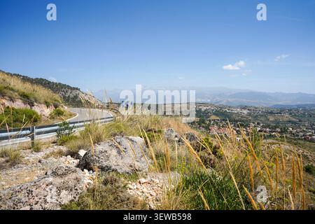 Gewundener Bergpass an den Hängen der Sierra de Huetor mit Gebirgszug der Sierra Nevada im Hintergrund, Andalusien, Spanien. Stockfoto