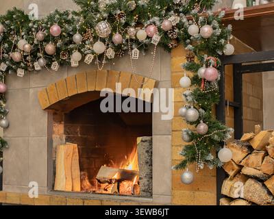 Gemütliche Weihnachtsszene mit einem dekorativen Kamin, geschmückt mit Ornamenten, Girlanden und Holzscheiten, der Wärme und Festtagsstimmung ins Haus bringt Stockfoto