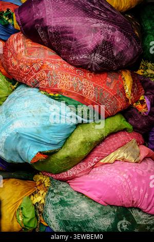 Diese Nahaufnahme zeigt eine vertikale Anordnung aus gebündeltem Stoff, die lebendige Farben wie tiefes Violett, Rot-Orange mit weißen und grauen Patten zeigt Stockfoto
