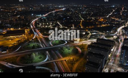 Luftaufnahme des Autobahnkreuzes bei Nacht mit langen Lichtspuren vom Verkehr in Porto, Portugal. Stockfoto