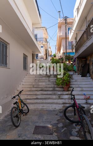 Vertikaler Blick auf zwei Fahrräder auf einer gepflasterten Straße am Fuße einer historischen, weiß getünchten Treppe, die mit grünen Pflanzen und blühenden Blumen dekoriert ist Stockfoto