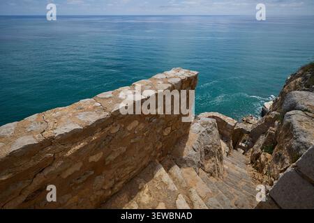 Das endlose türkisfarbene Mittelmeer und die Steintreppe, die von der Spitze der Klippe hinunter führt. Schloss Peniscola in der Provinz Castellon Valenci Stockfoto