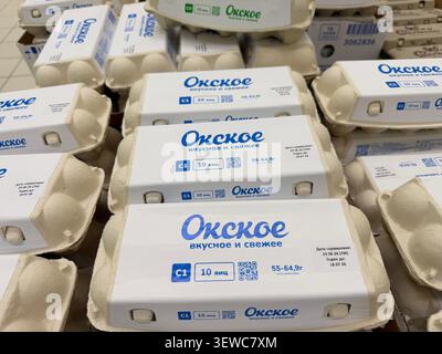 Eierkartons in einem Lebensmittelgeschäft gestapelt, mit blau-weißer Verpackung mit Etiketten in russischer Sprache und sichtbaren Produktinformationen Stockfoto