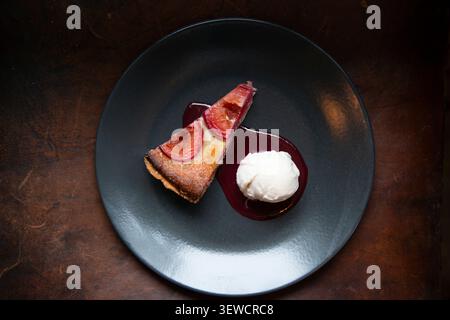 Köstliches Dessert mit cremiger Vanilleeis und einem Stück Fruchttorte Stockfoto