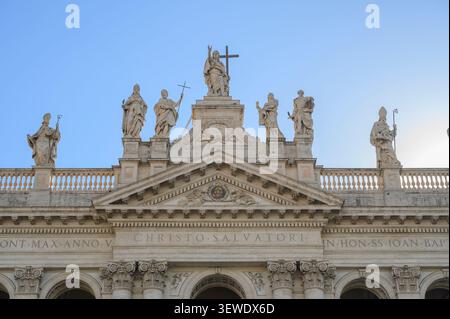 Detail der monumentalen Statuen und des zentralen Tympanons auf der Dachlinie der Fassade der Archbasilika San Giovanni in Laterano in Rom, Italien Stockfoto