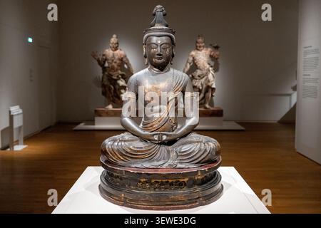 Amsterdam, Niederlande - 15. April 25: Sitzende Buddha-Skulptur in einer Galerie des Rijksmuseums mit anderen asiatischen Kunstwerken, Amsterdam, Niederlande. Stockfoto