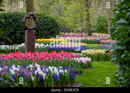 Großer Blick auf die lebendigen Tulpen- und Hyazinthen-Betten mit moderner Metallskulptur in den Keukenhof Gardens, Lisse, Südholland, Niederlande. Stockfoto