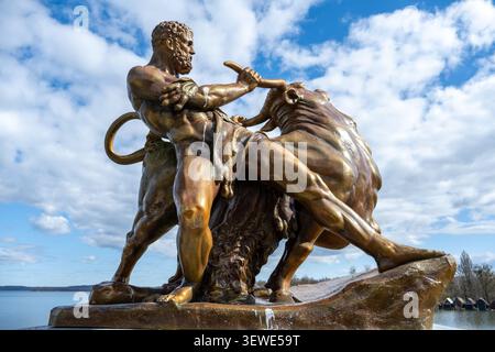 Bronzestatue, die einen muskulösen Mann zeigt, der einen Stier ringt, fotografiert auf dem Gelände des Schweriner Schlosses mit See und Himmel im Hintergrund, Deutschland. Stockfoto