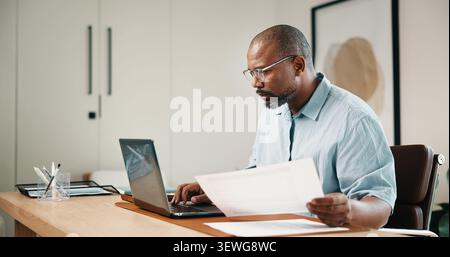 Laptop, Dokument und schwarzer Mann im Home Office mit Remote-Arbeit, Verwaltung oder Recherche zur Steuervorbereitung. Freiberufler, reifer Mensch und Computer im Haus Stockfoto