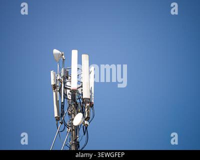 Weiße Panels und Antennen stehen hoch am Himmel. Auf Metallrahmen montierte Strukturen signalisieren starke Konnektivität. Ideal für Technik und Infrastruktur Stockfoto
