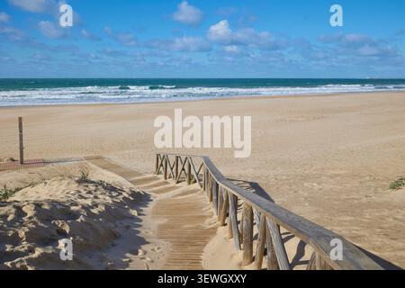 Breiter Sandstrand am Meer. Holzweg führt zum Strand. Stockfoto