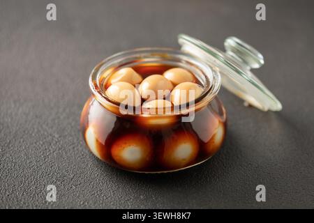 Hausgemachte, braun marinierte, eingelegte Wachteleier im Glas auf dem Tisch. Asiatische Küche Stockfoto