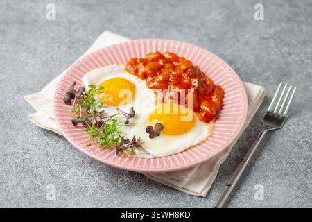 Kontinentales Frühstück: Eier, Mikrogemüse und Bohnen in Tomatensauce auf einem Teller auf dem Tisch. Gesundes Frühstück Stockfoto