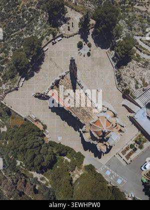 Blick aus der Vogelperspektive auf Santuario de Santa Maria Magdalena, umgeben von einem gepflasterten Innenhof und üppigen Bäumen in Novelda, Comunidad Valenciana, Spanien. Stockfoto