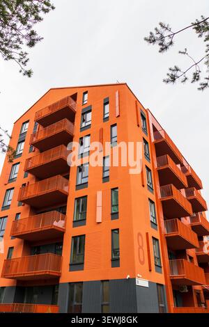 Flacher Blick auf eine moderne, helle orange Wohnhausfassade mit symmetrischen Balkonen und minimalistischer skandinavischer Architektur. Stockfoto