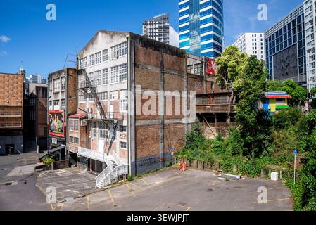 Altes Backsteingebäude mit Feuertreppe und moderner Skyline, Auckland, Neuseeland, 1. Januar 2024 Stockfoto