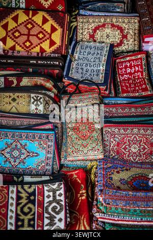 Eine Nahansicht von oben zeigt eine dicht gepackte Sammlung kleiner Textilwaren, darunter Geldbörsen, Beutel und kleine Taschen, mit komplizierten ta Stockfoto