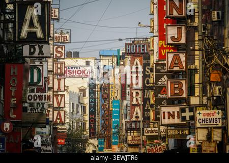 INDIEN, DELHI - 10. März 2017: Zahlreiche vertikal gestapelte, verwitterte Metall- und Neonschilder für Hotels und verschiedene Unternehmen drängen sich teilweise zusammen Stockfoto