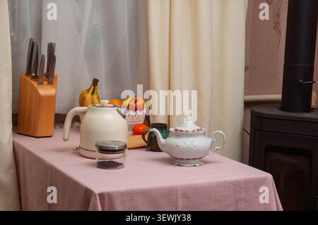 Eine warme und einladende Küchenzeile mit Teekanne, Wasserkocher, Obstschale und Messerblock, perfekt für eine morgendliche Routine Stockfoto
